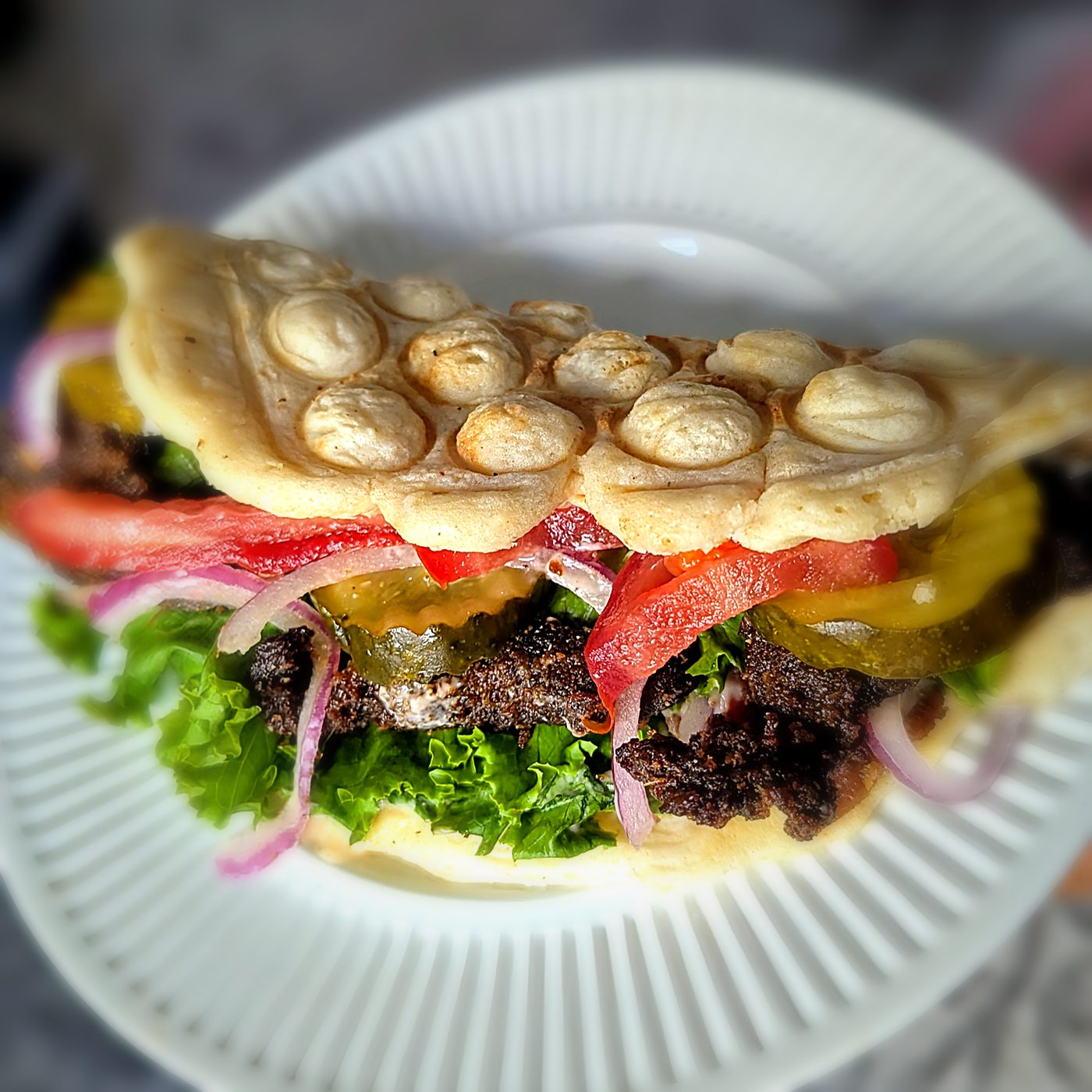 Gaufre La Gauchère au suya de bœuf, tomates, oignons rouges, laitue et cornichons